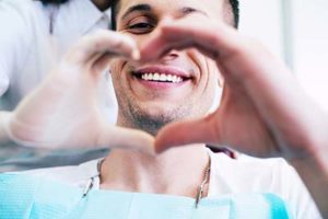 A man and his dentist make a heart with their hands after they talk about Lovett Dental Vintage Park