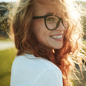 A woman in glasses looks behind her and smiles after receiving dental services at Lovett Dental Vintage Park