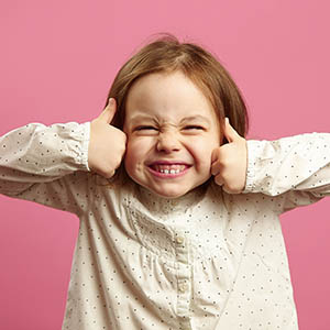 A little girl holds up two thumbs after receiving dental services in Lovett Dental Vintage Park