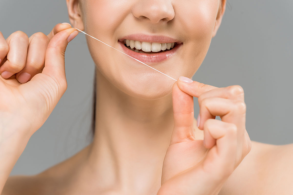 benefits of flossing daily a woman prepares to floss as she thinks of the benefits of flossing daily