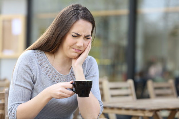 common dental problems a woman drinks tea and suffers common dental problems