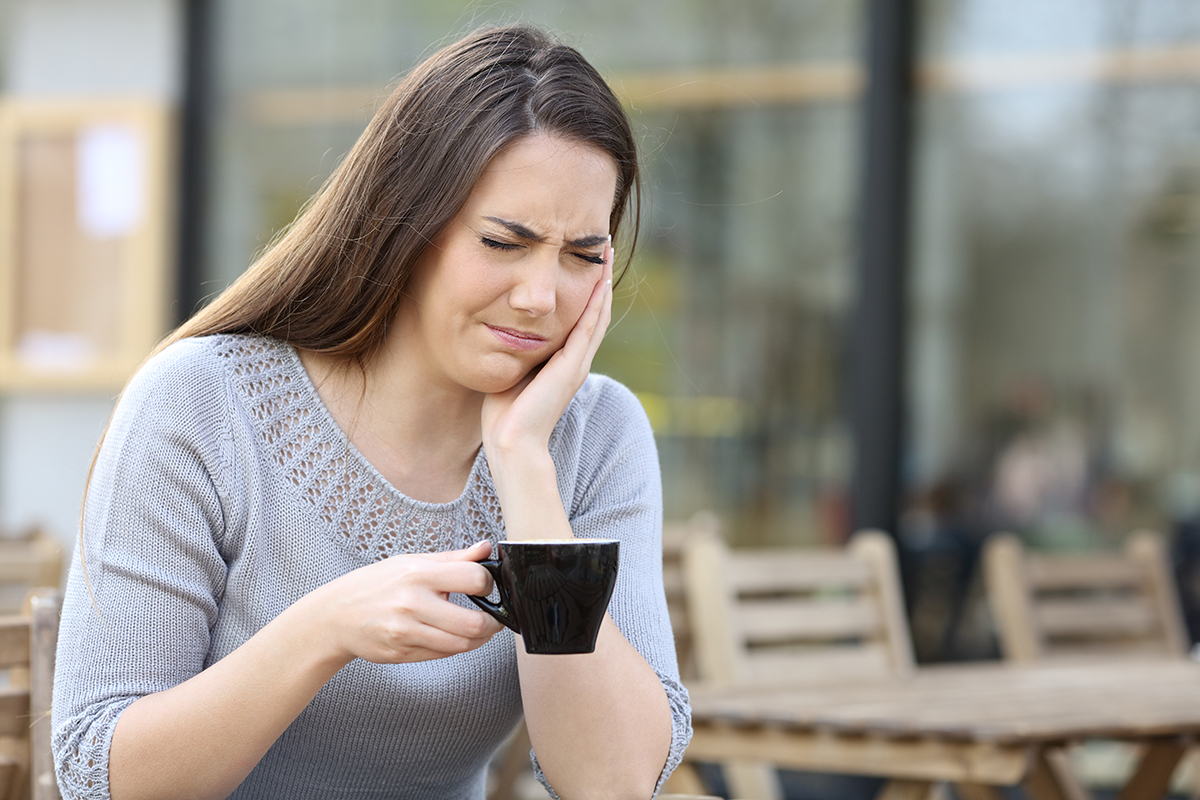 a woman drinks tea and suffers common dental problems
